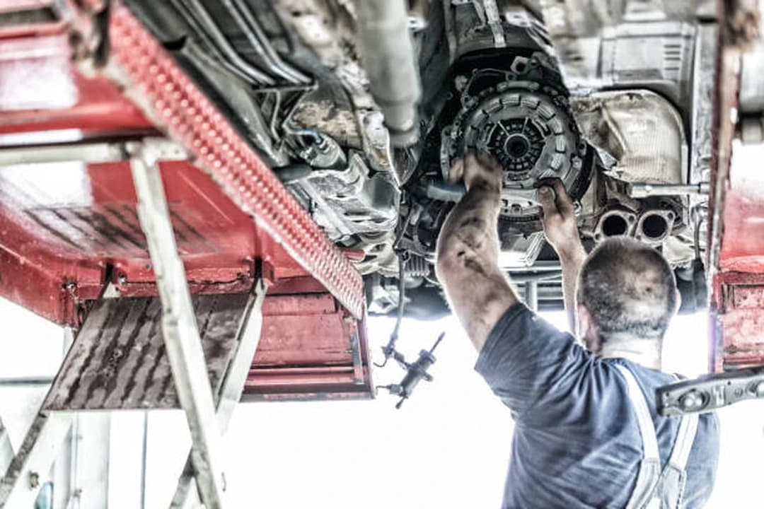 Technician fitting a clutch friction plate beneath a vehicle on a ramp at Brilliant Motors Garage, Welling
