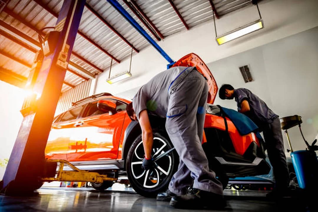 Technicians servicing a car on a workshop lift at Brilliant Motors Garage in Welling, Kent