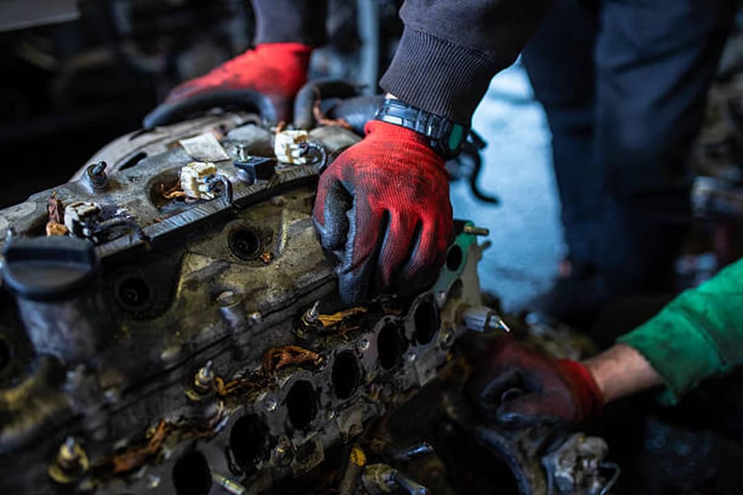 Technicians stripping a cylinder head from an engine block during engine reconditioning at Brilliant Motors Garage in Welling